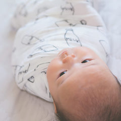 Minination swaddle blanket in crib demonstrating generous 47x47 inch coverage.
