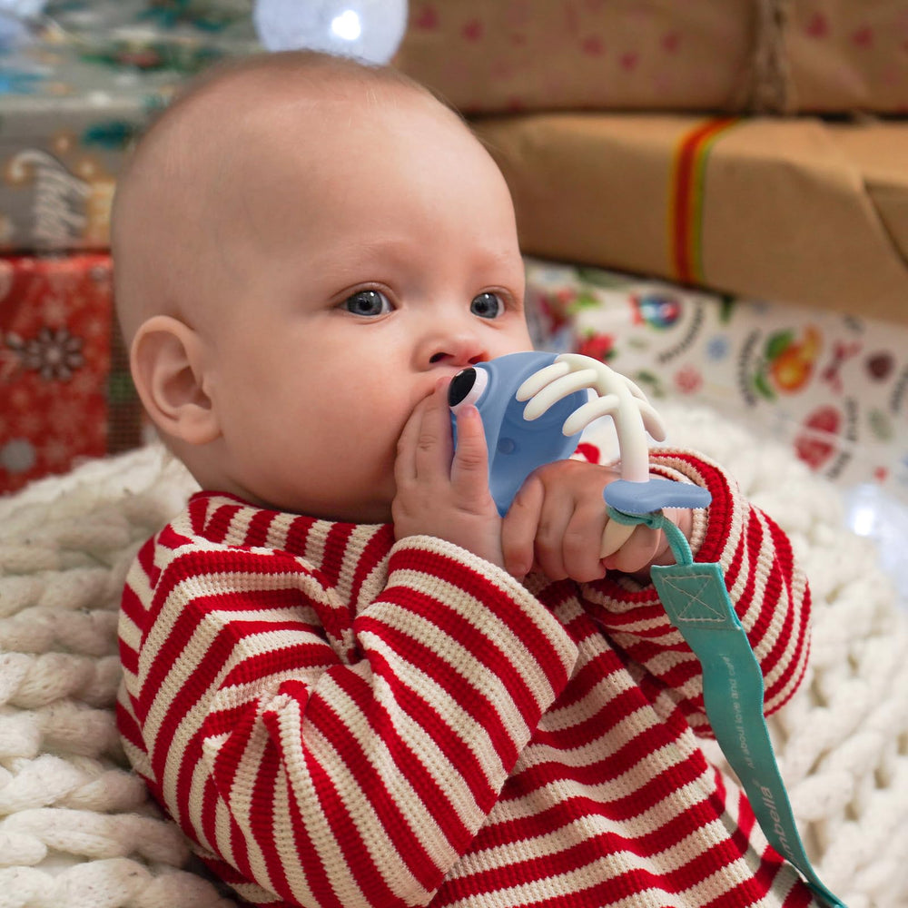 Mombella teething toy blue held in hand for easy grasp and self-soothing.