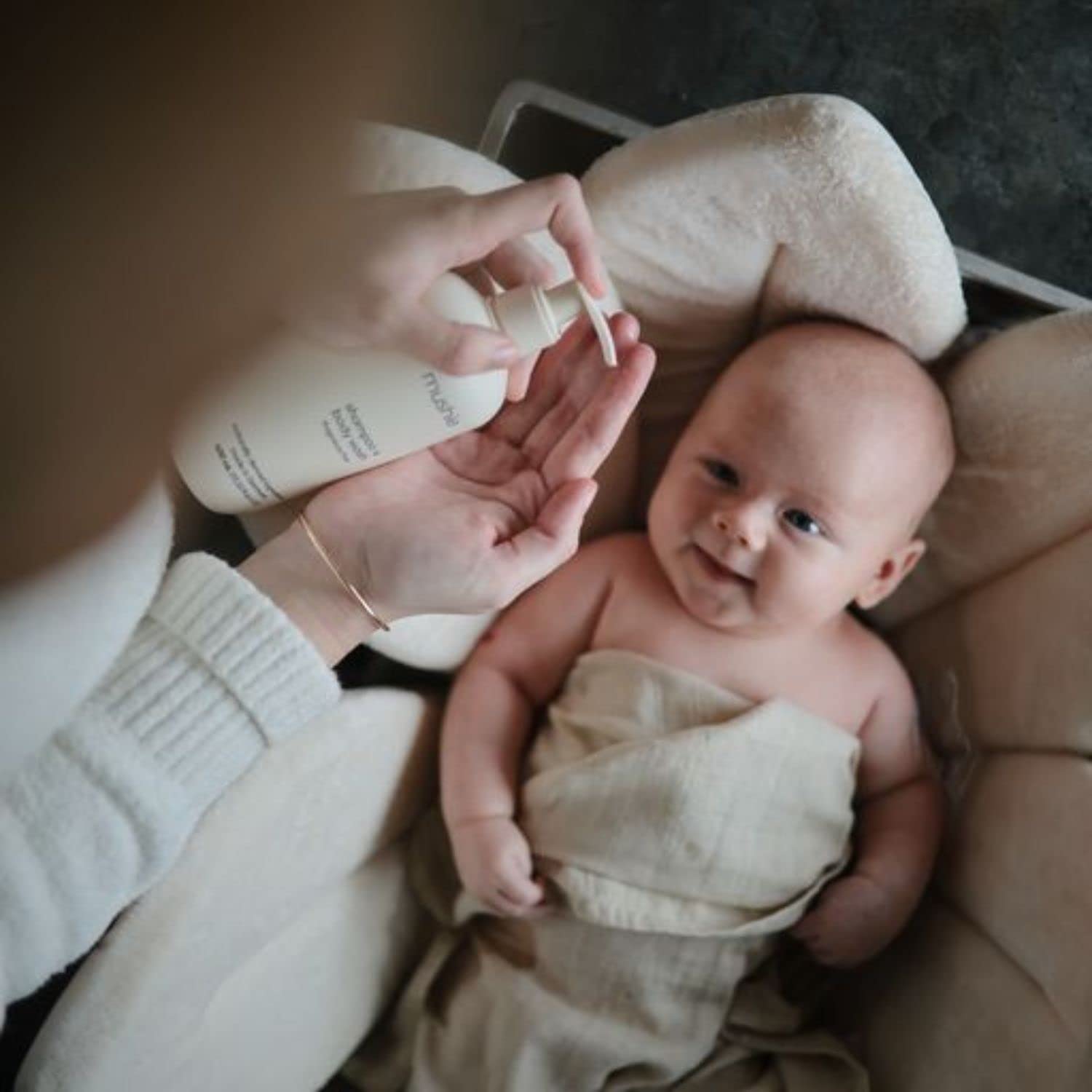 Pouring Mushie shampoo into bath water to soften and cleanse gently