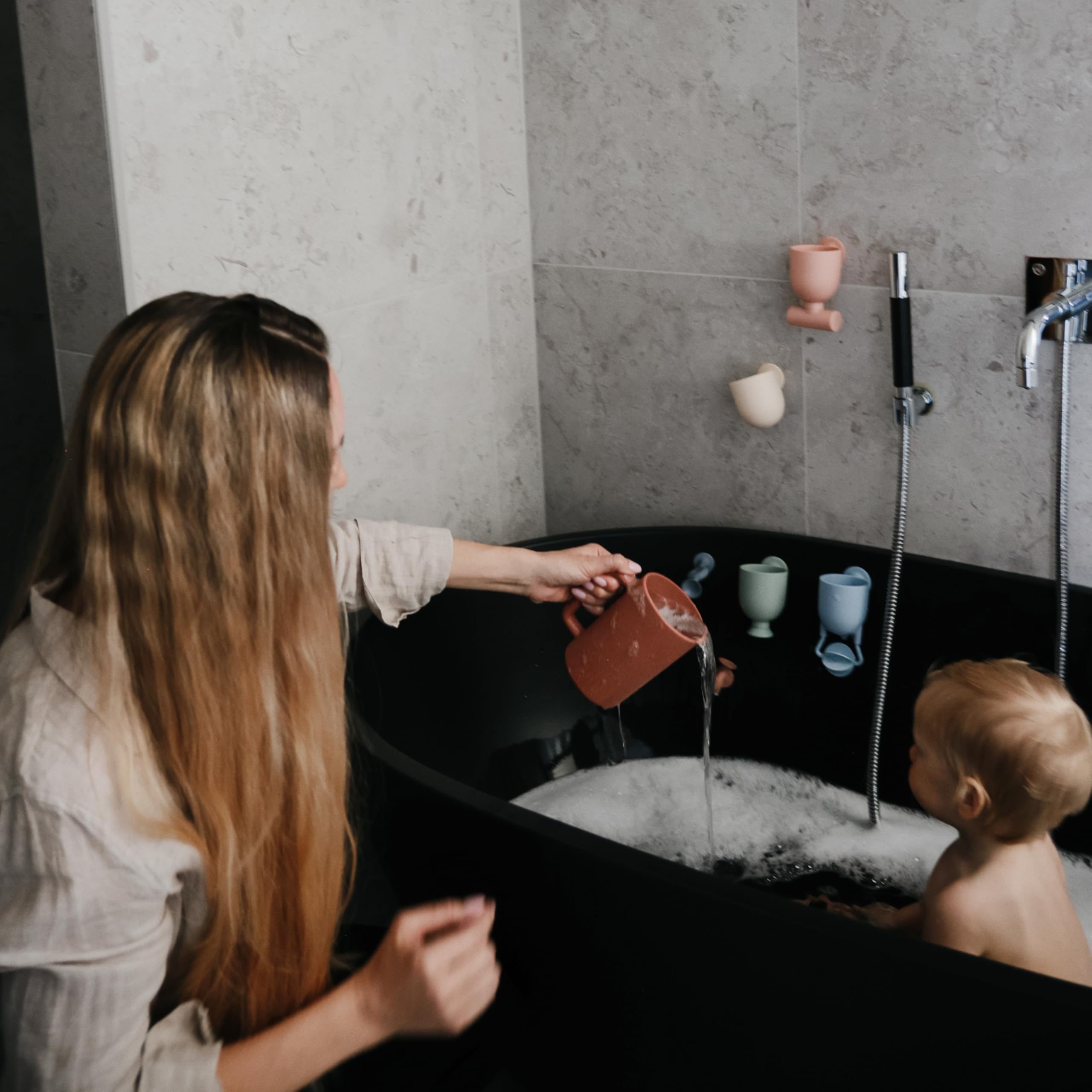 Mushie bath rinse cup demonstrates pouring action for soap and suds-free rinse.