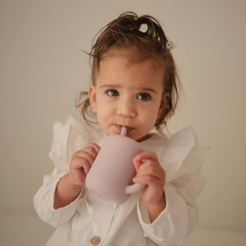 Little hands grip the cup securely, supporting fine motor skill development.