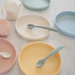 Mushie Classic Silicone Suction Plate stone mealtime scene with toddler self-feeding.