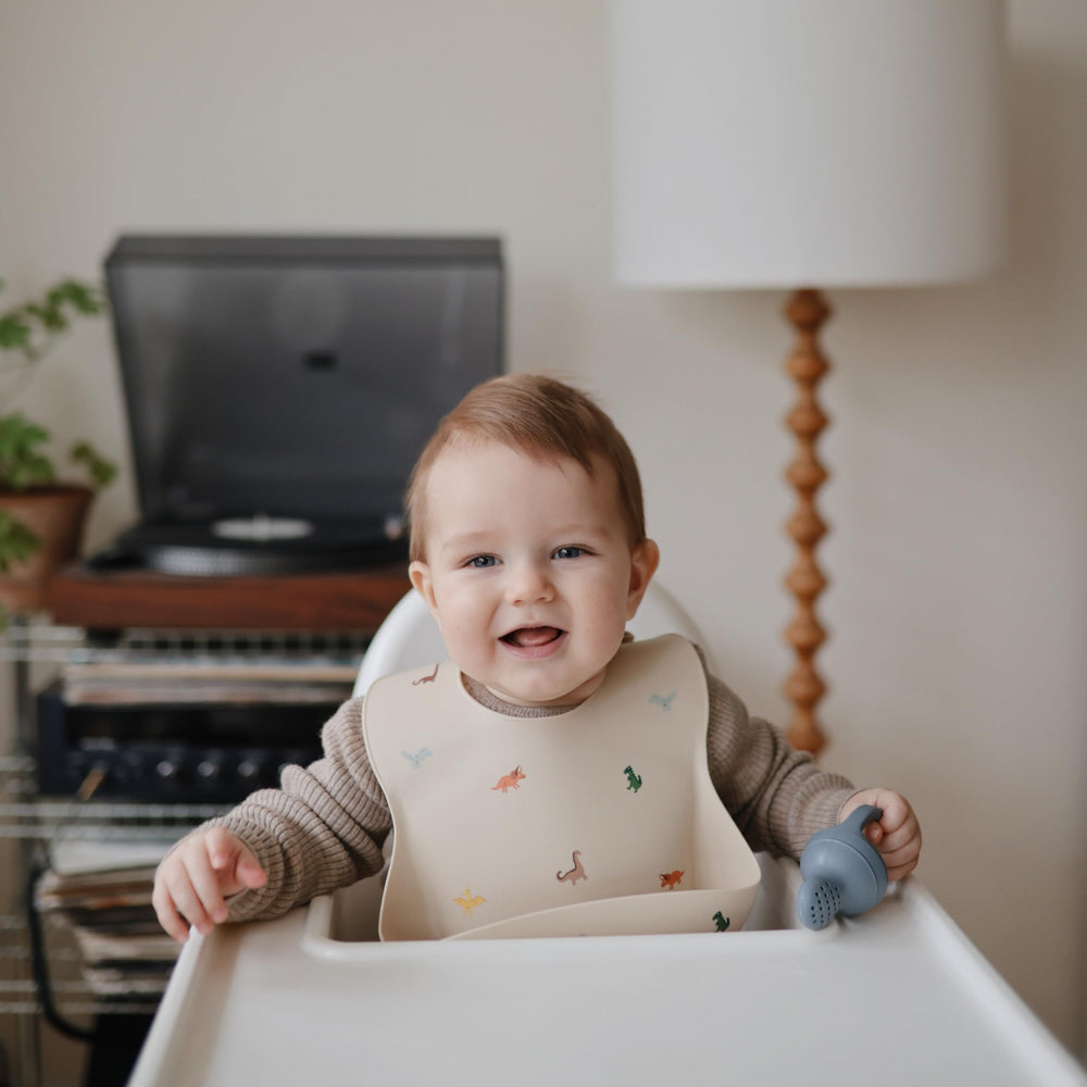 Mushie dinosaur bib resists stains and dries quickly after meals.