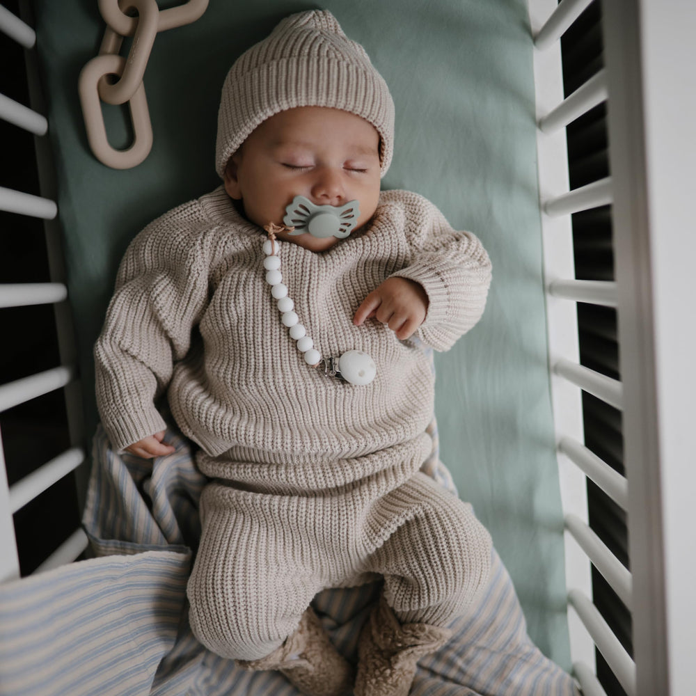 Mushie elastic-edge fitted mini crib sheet demonstrates secure fit on rectangular mattress