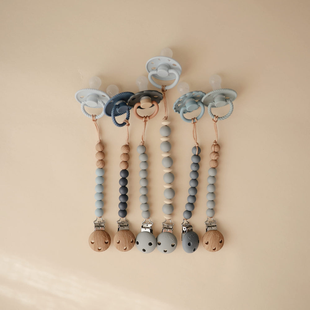 Mushie Eva two-tone beads offer a gentle grip on the pacifier.