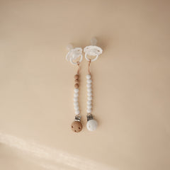 Mushie Eva pacifier clip with molded clasp for secure attachment.