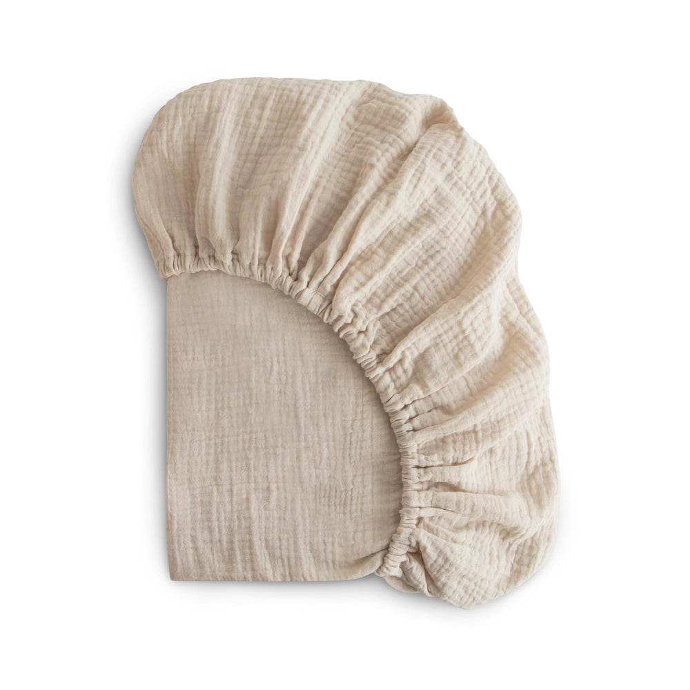 Mushie extra soft muslin fitted mini crib sheet Fog on mattress for breathable comfort.