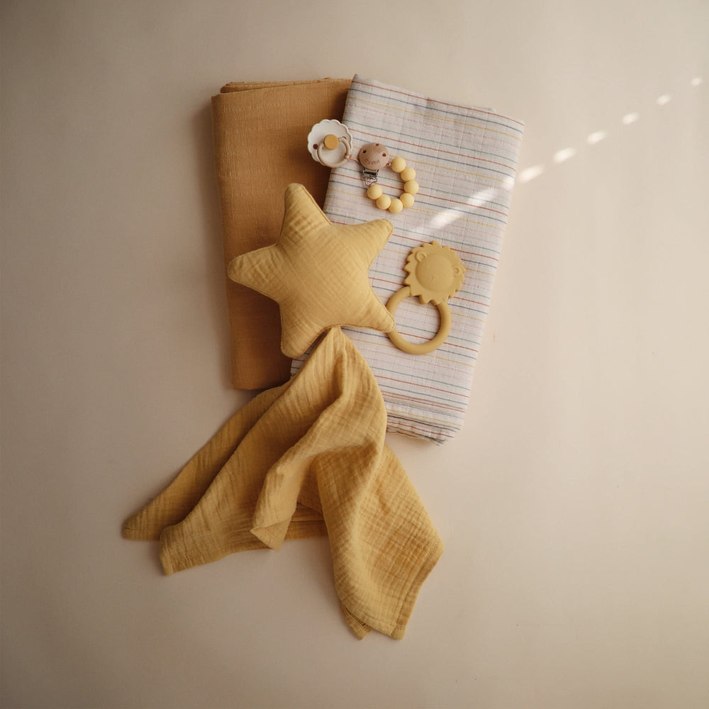 Mushie Lion teether in hand ideal for on-the-go soothing.