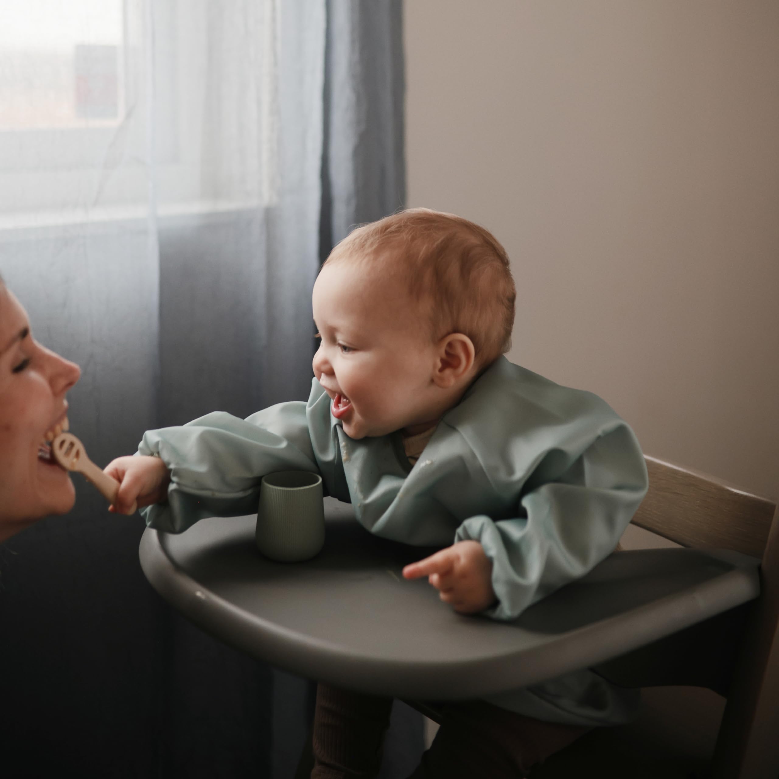 Mushie long sleeve bib in Roman Green folded flat for compact storage