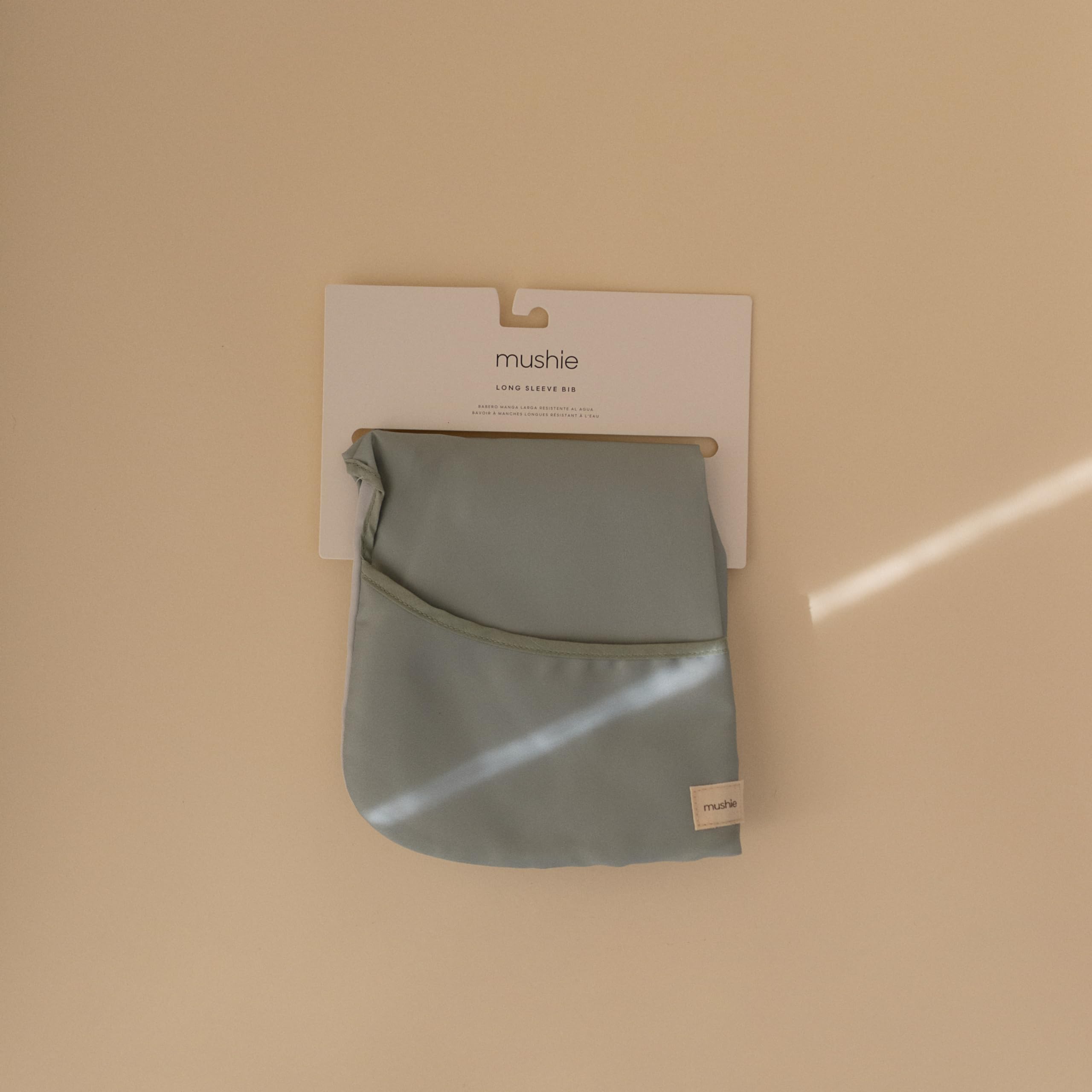 Mushie long sleeve bib in Roman Green demonstrates secure Velcro neck closure