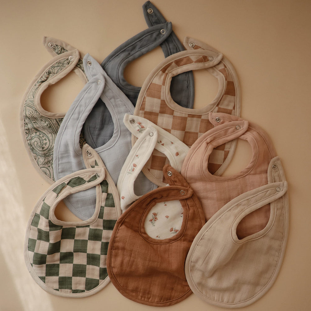 Mushie bib during meals helps control spills with soft fabric.