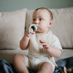 Mushie muslin bib close-up reveals multi-layer absorbent fabric for spills.