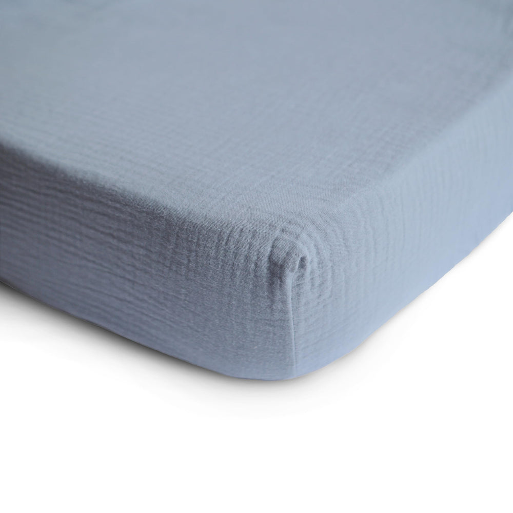 Mushie muslin fitted mini crib sheet Tradewinds shows elastic edges for secure fit