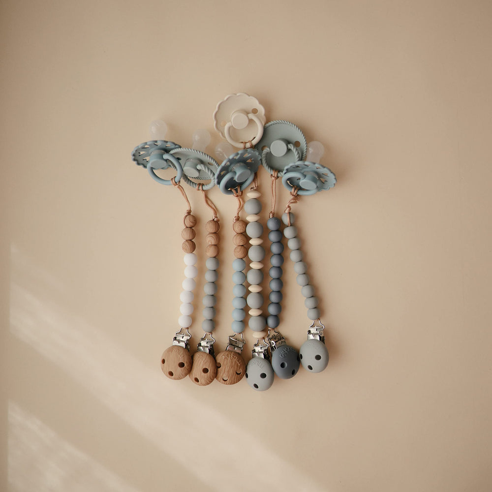 Mushie Eva pacifier clip supports on-the-go care for babies.