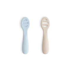 Mushie packaging view of silicone first feeding spoons in powder blue and shifting sand colors for mealtime prep.