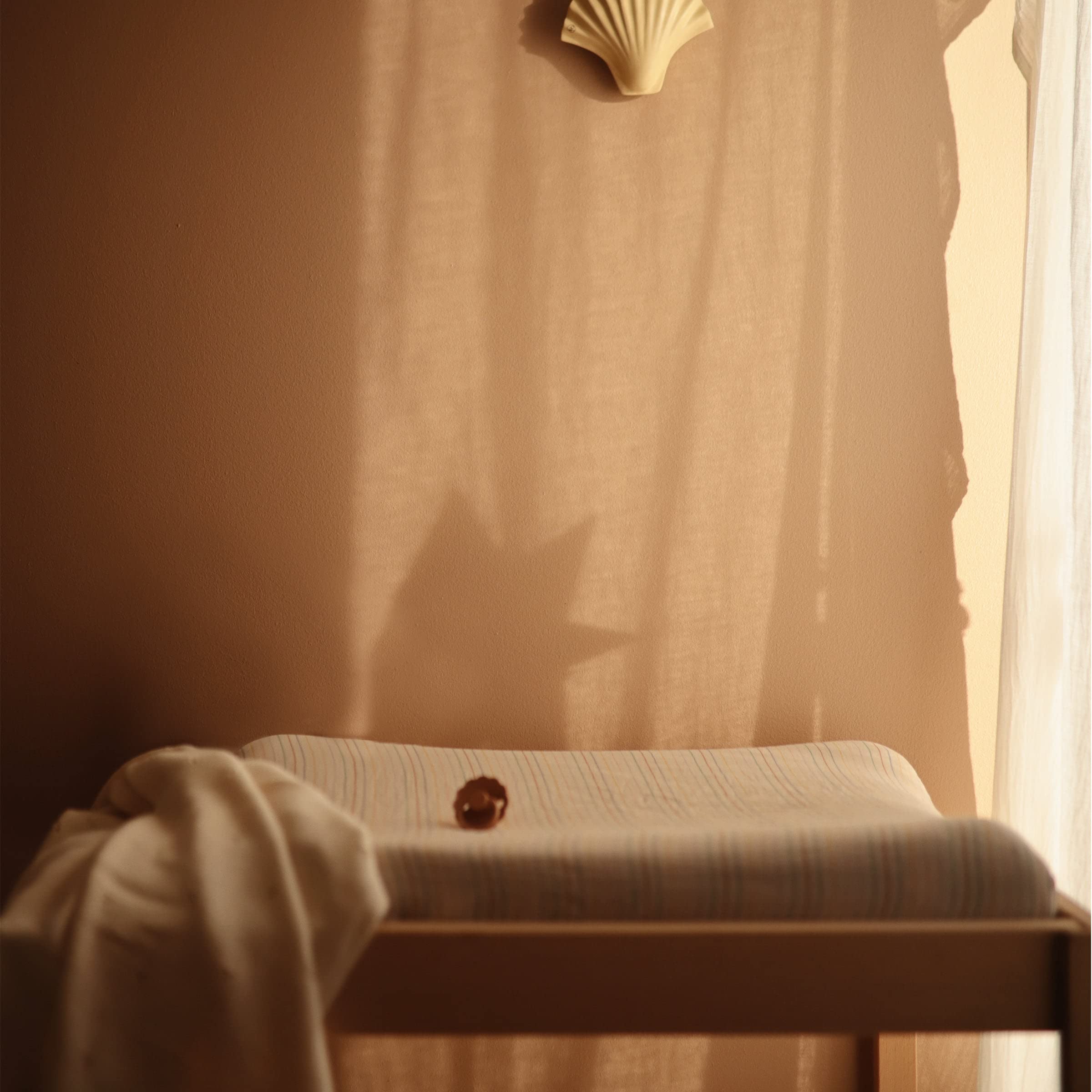 Mushie Rainbows cover on a standard changing pad for versatile use.