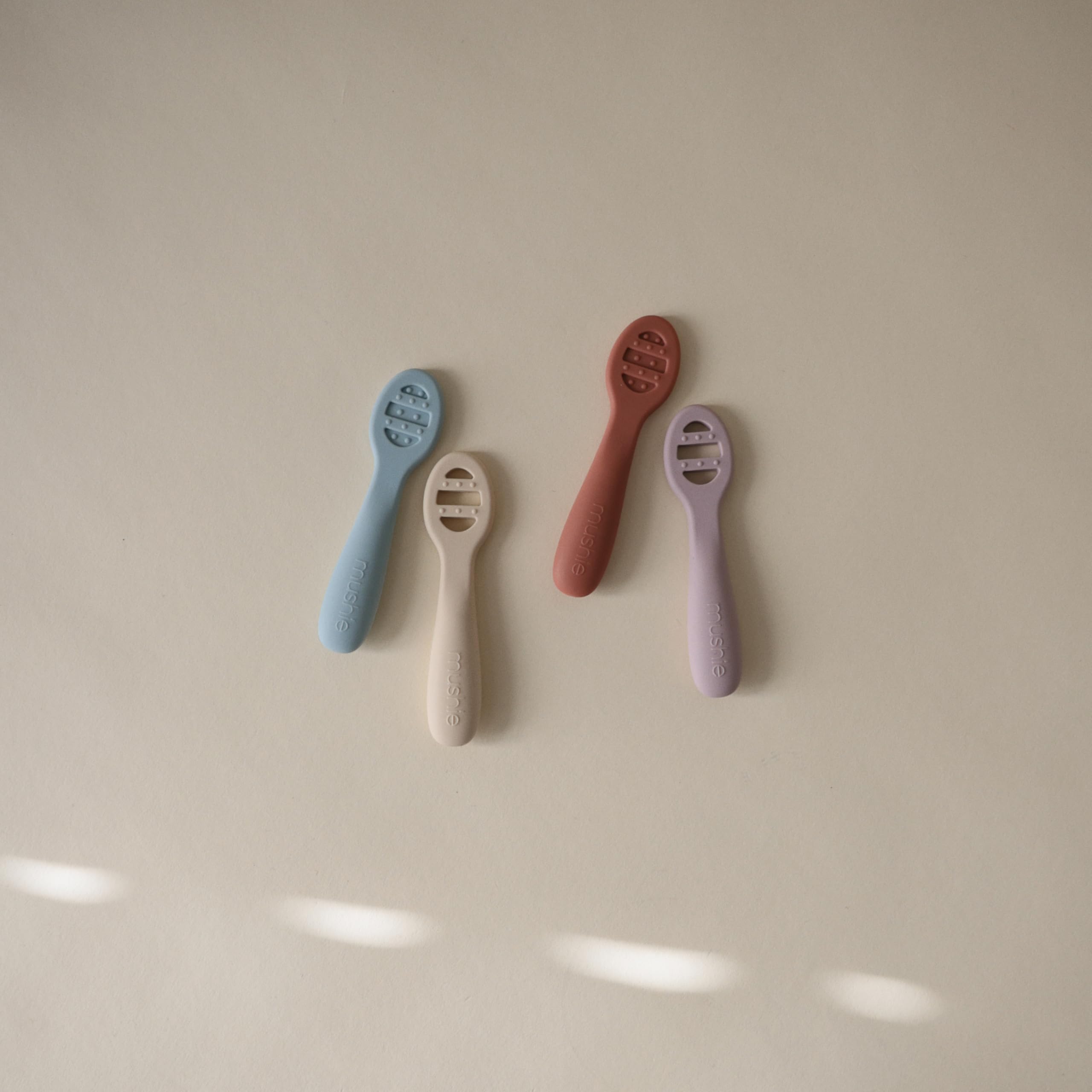 Mushie silicone spoons with sensory dots soothe teething gums.