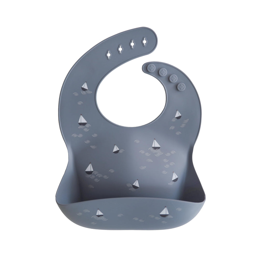 Mushie silicone baby bib adjustable fit with boats pattern, keeps mess in the pocket.