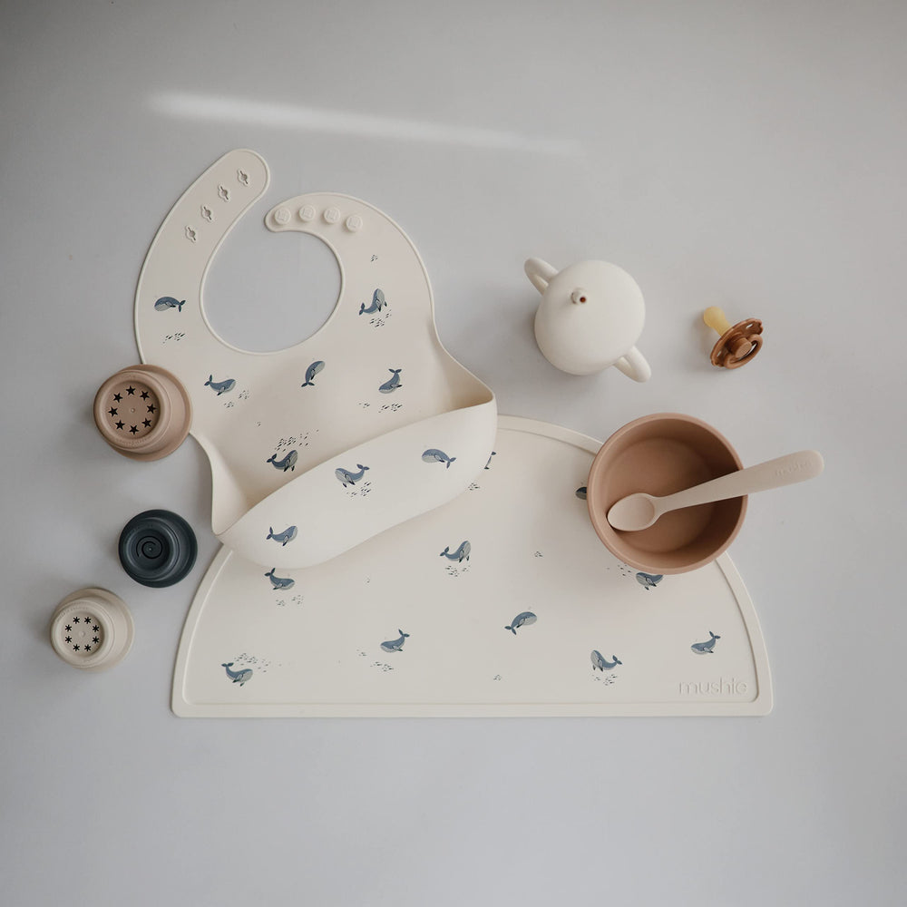 Mushie adjustable-neck silicone bib provides a snug fit to reduce slips.