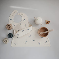 Mushie adjustable-neck silicone bib provides a snug fit to reduce slips.
