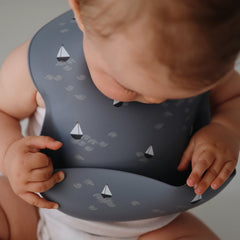 Mushie bib soft neck fasteners closeup, boats pattern, gentle on baby's neck.
