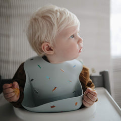 mushie silicone baby bib waterproof keeps outfits dry during meals.