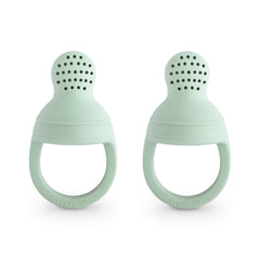 Mushie silicone baby feeder two-pack for safe self-feeding with fresh fruit.