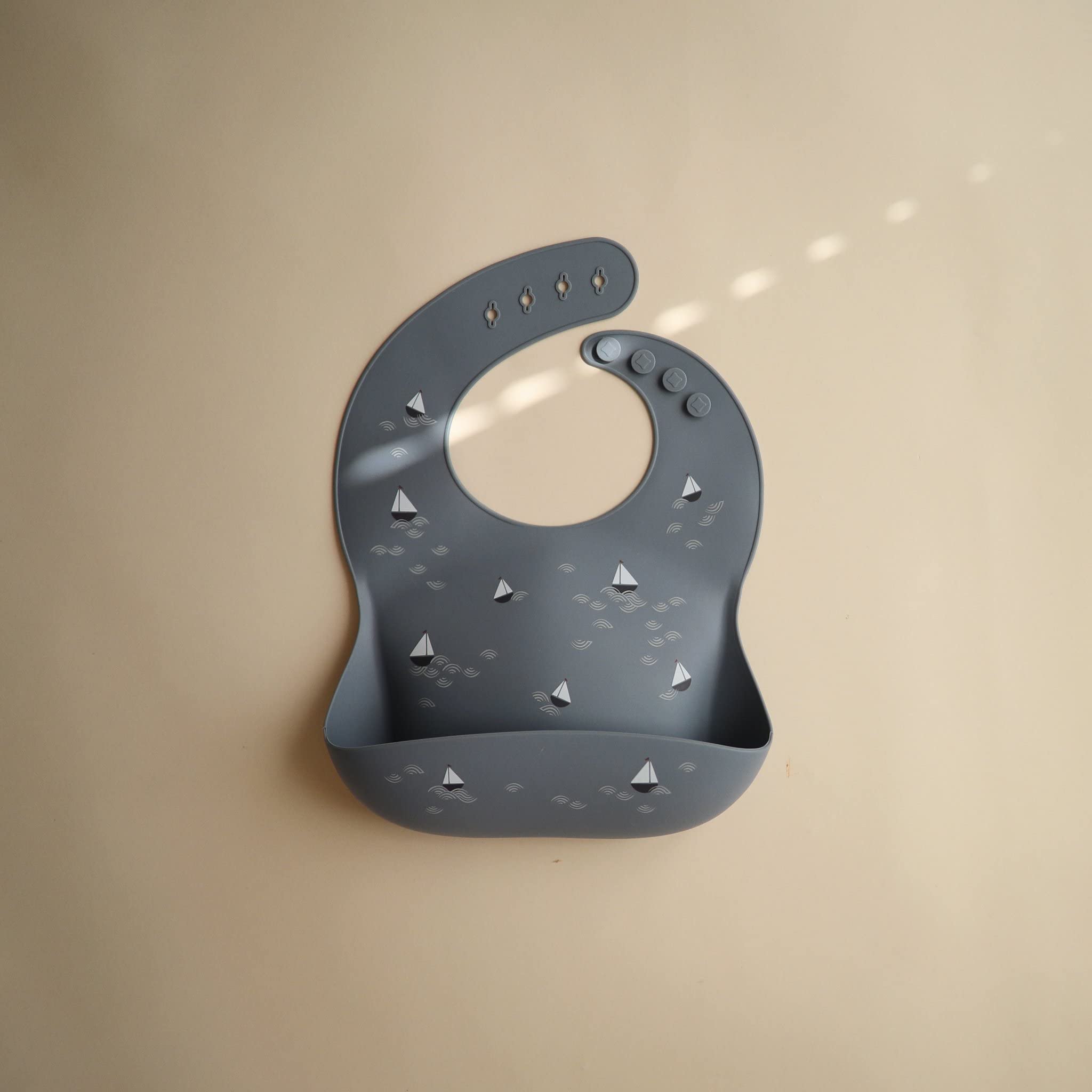 Mushie BPA-free silicone bib, boats design, safe for baby meals.