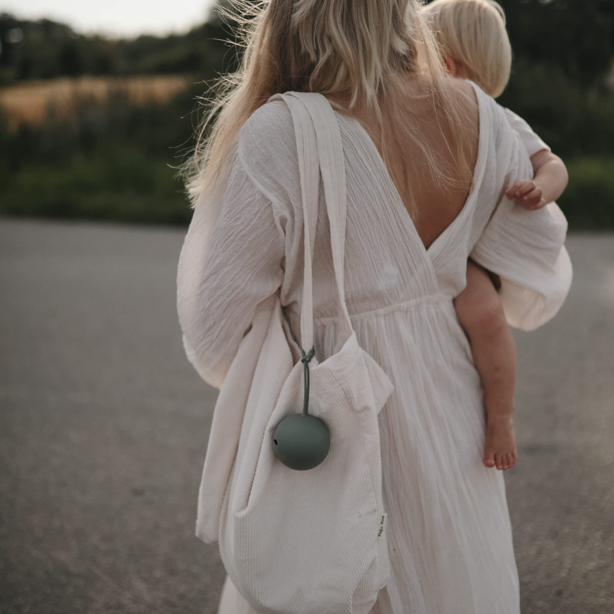Mushie pacifier holder attached to stroller for hands-free organization