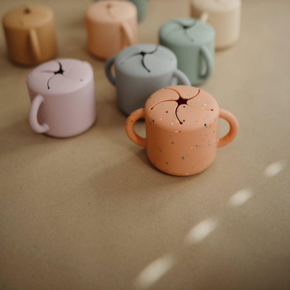 Mushie silicone snack cup dishwasher-safe for easy cleaning.