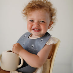 Mushie silicone snack cup, soft colors, helps little hands grip and self-feed.