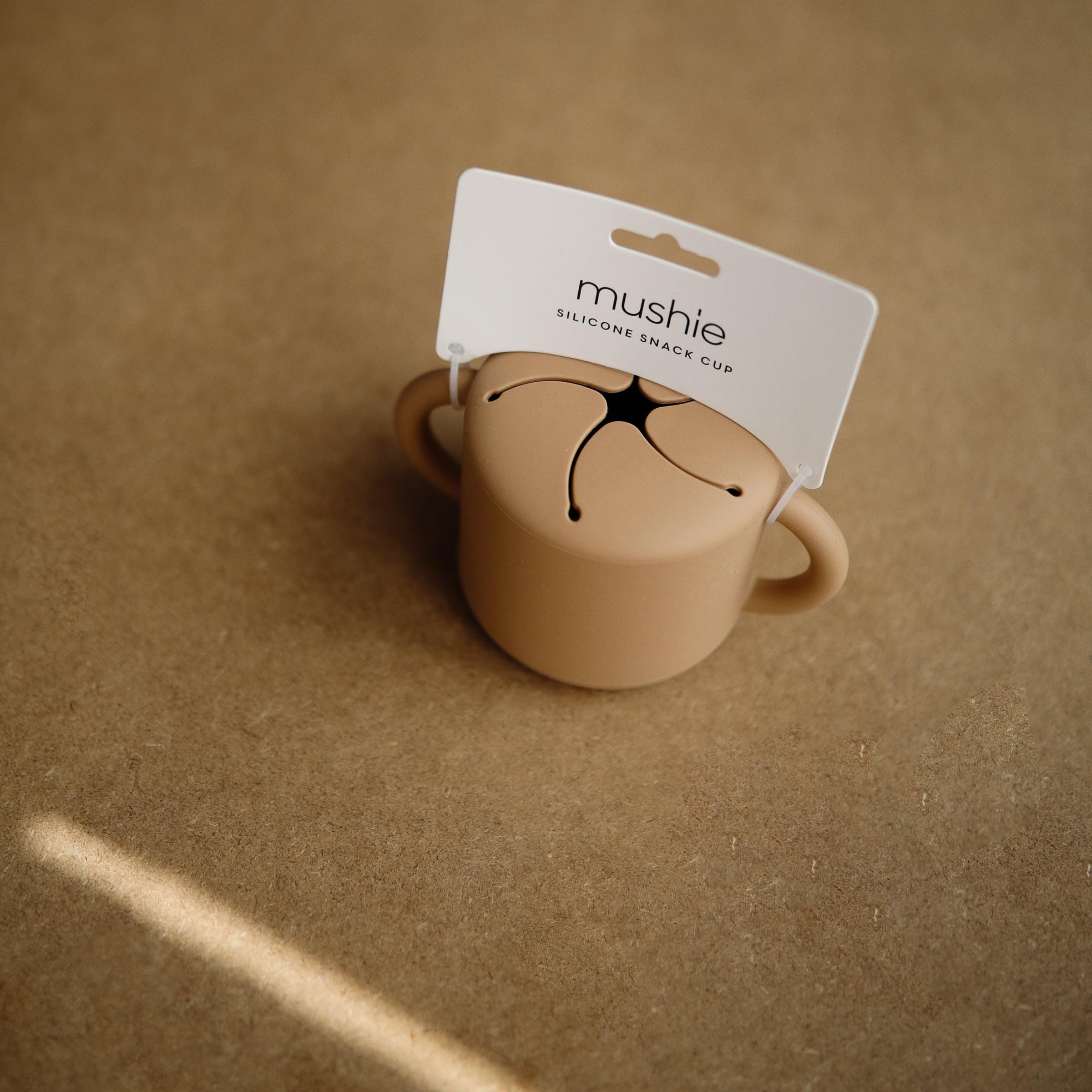 Mushie snack cup in soft colors enhances early feeding experiences.