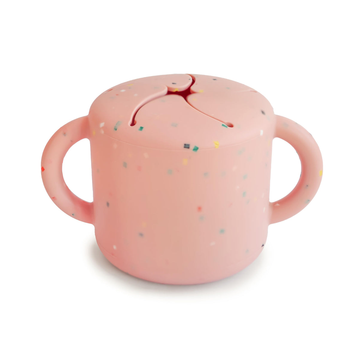 Mushie silicone snack cup with two handles helps toddler grip during on-the-go snacking.