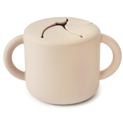 Mushie silicone snack cup with two handles, spill-proof for toddlers on the go.