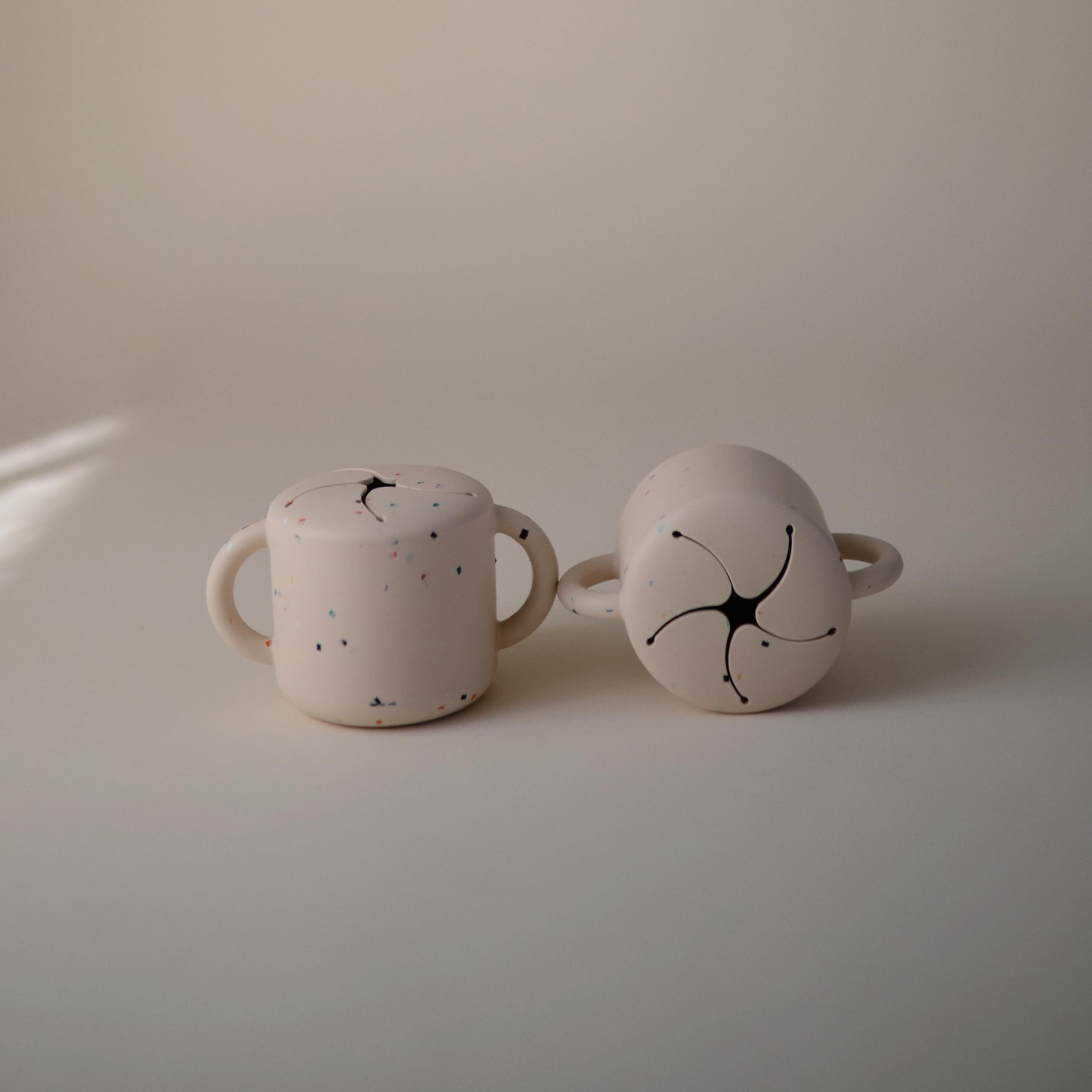 Mushie soft-opening snack cup for easy reach by small hands.