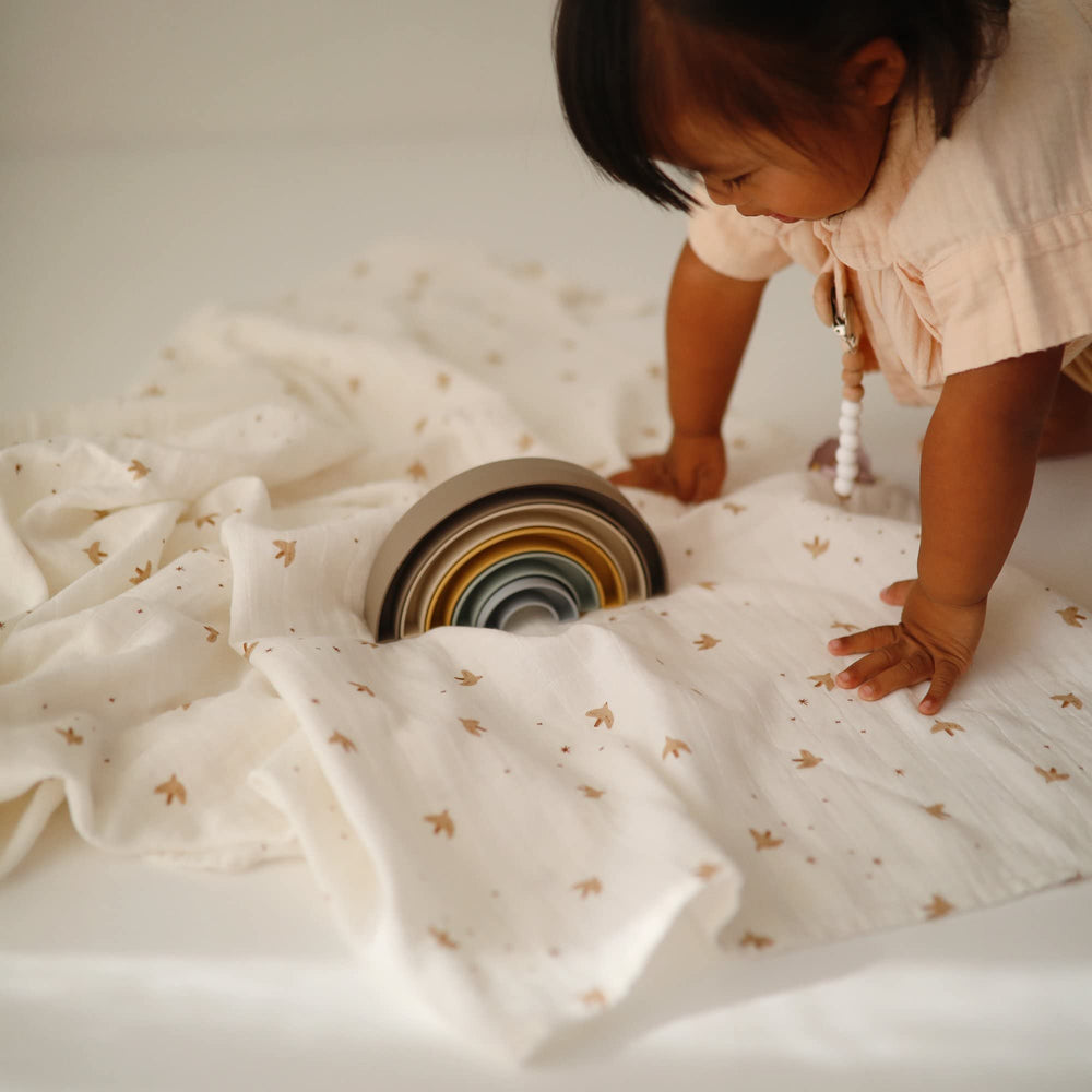 Mushie Sparrow muslin swaddle offers nursery-ready versatility for swaddling, nursing, and cuddling.