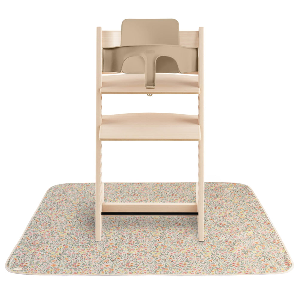 Mushie Splat Mat Pastel Blooms under high chair catching spills for easy cleanup