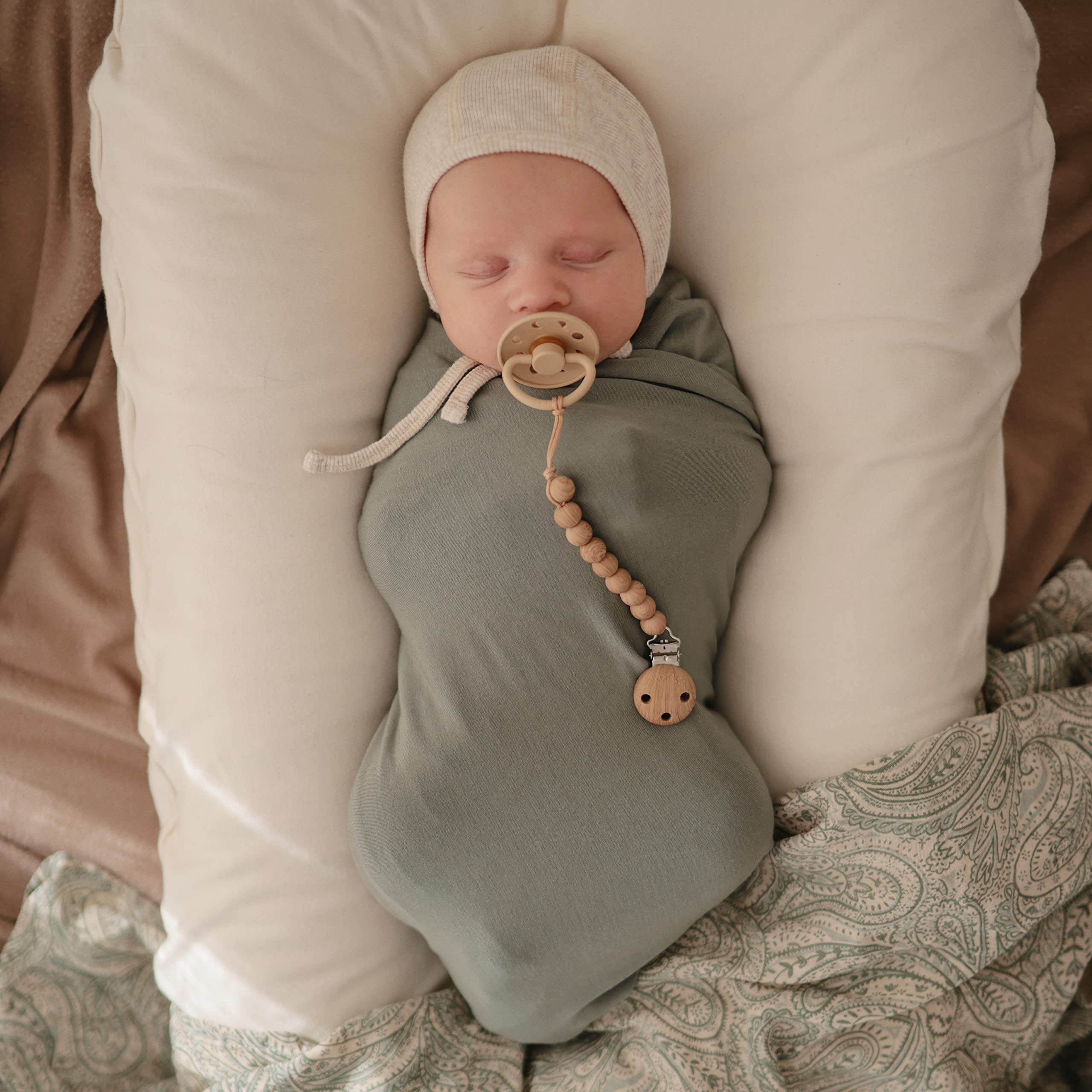 Baby wrapped snugly in Mushie Stretchy Swaddle for secure swaddling.