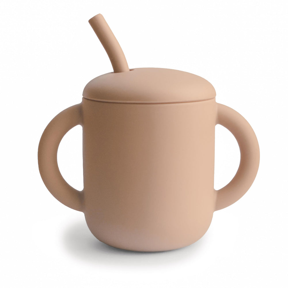 Mushie training cup with spill-proof lid protects surfaces during meals.