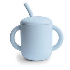 Mushie powder-blue training cup with lid for spill-free sipping.