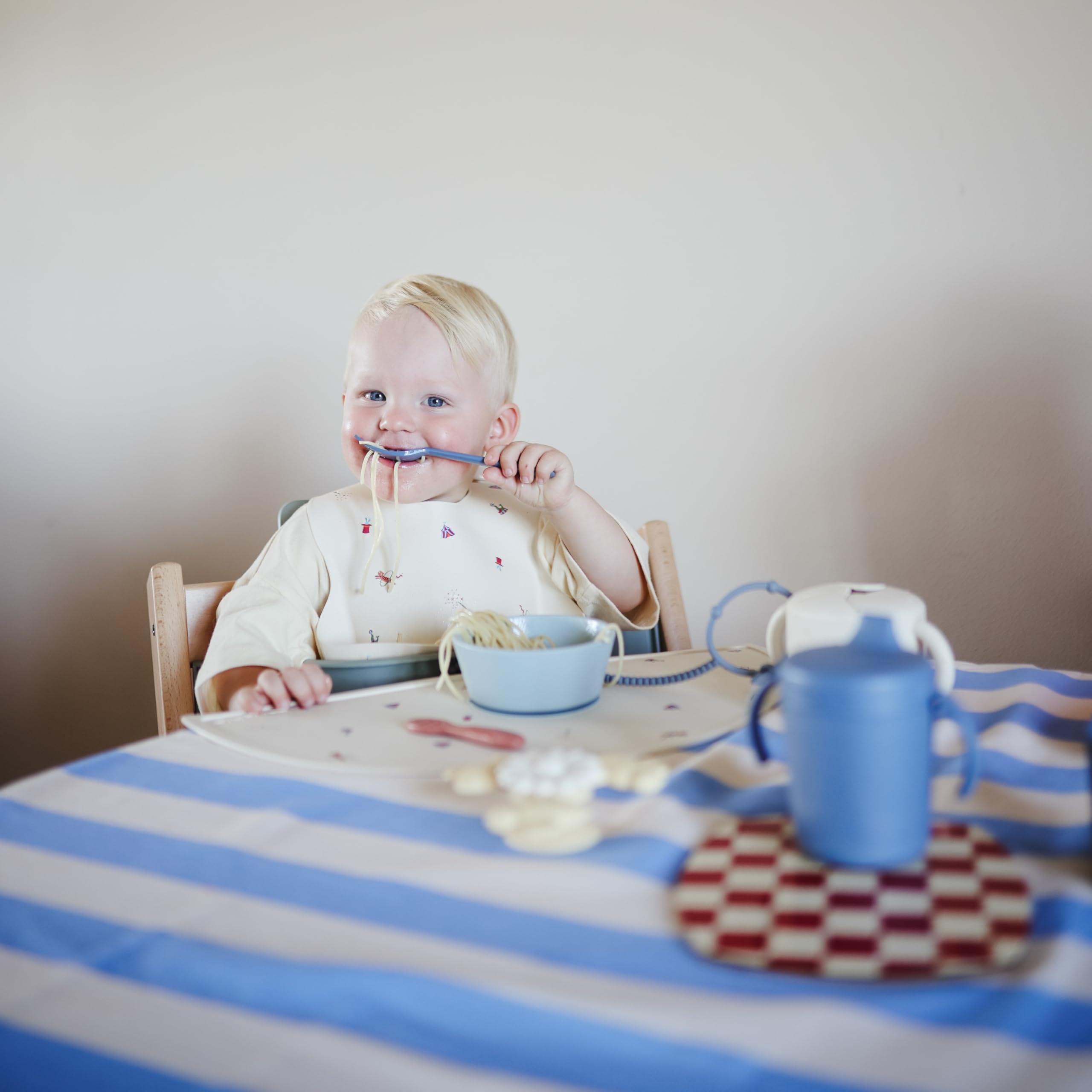 Mushie Twilight Blue child holding flatware during mealtime