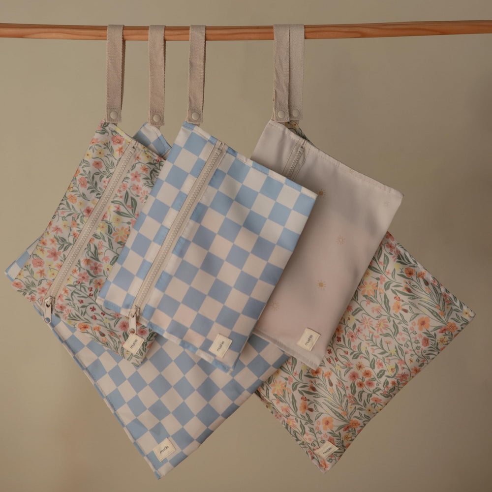 Mushie blue-check wet bag open view with handle for stroller attachment.