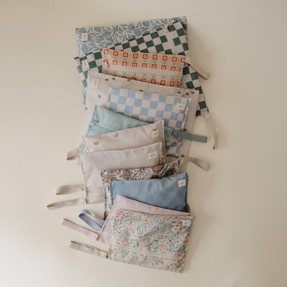 Mushie wet bags with snap handles for stroller attachment.