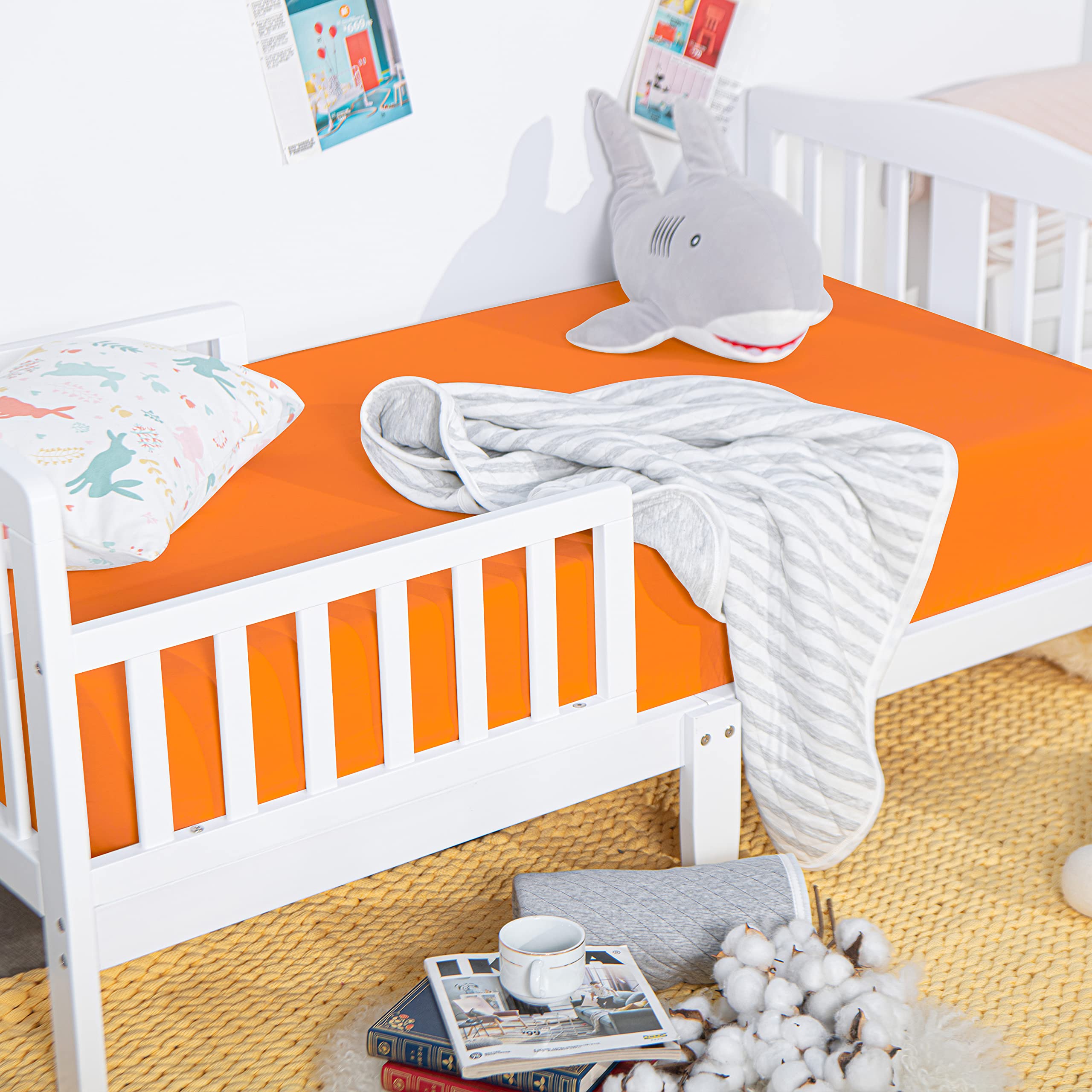 NTBAY orange crib sheet on standard crib mattress showing secure fit.