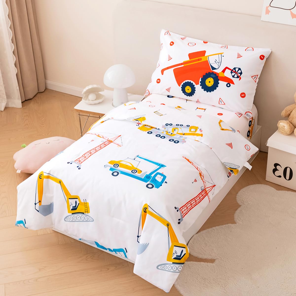 PERFEMET reversible trucks and cranes bedding on white crib setting for versatile decor.