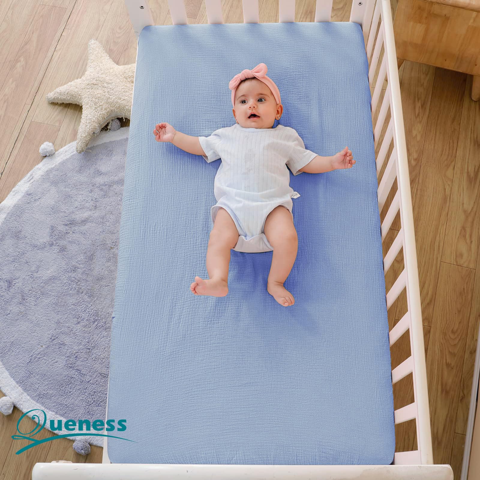 QUENESS muslin crib sheet close-up shows light, airy fabric detail.