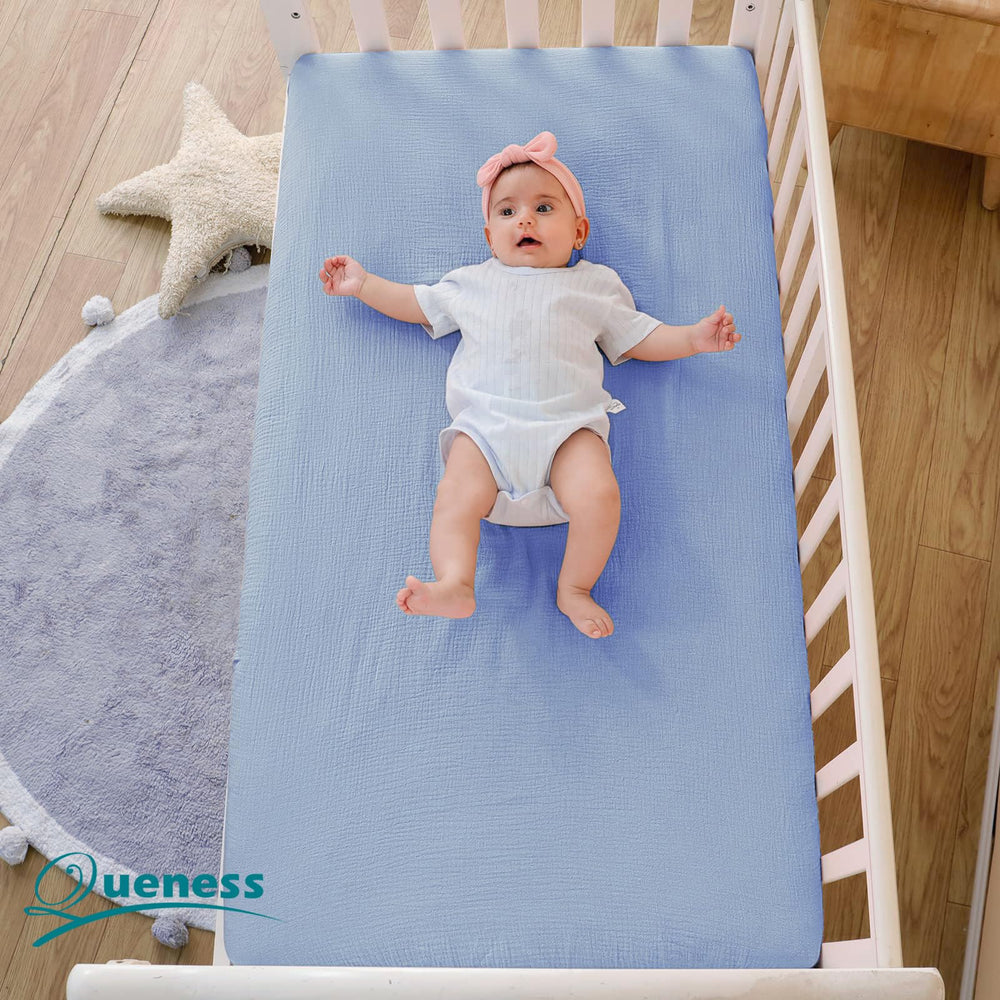 QUENESS muslin crib sheet close-up shows light, airy fabric detail.