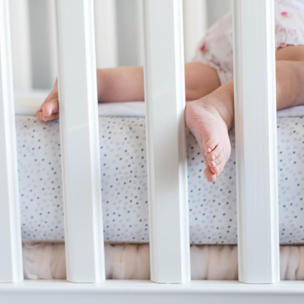 Ivory sheet on standard crib mattress illustrating universal fit.