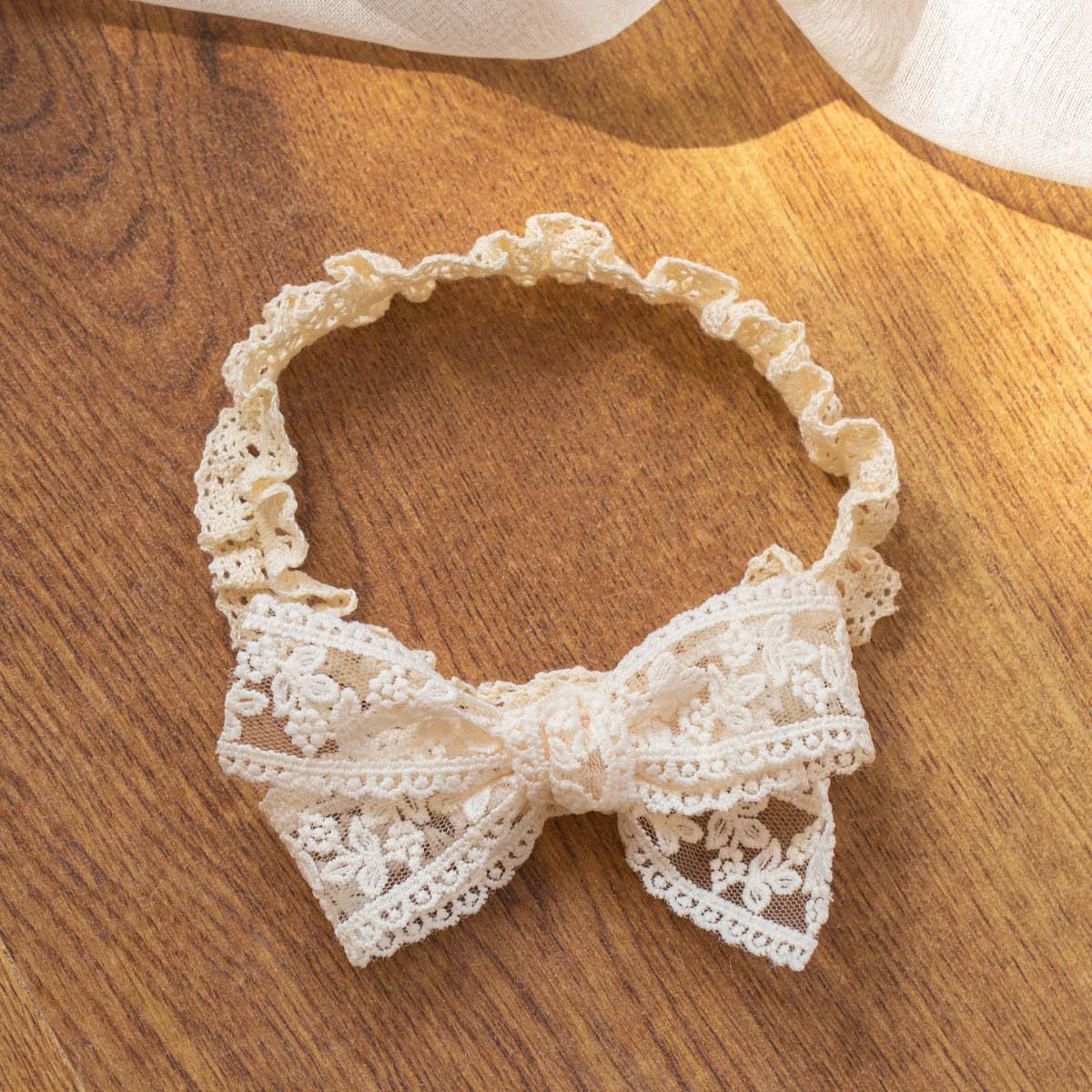 Baby wearing Rannyrena lace headband with adjustable fit for 0-24 months.