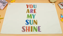 Sioial You Are My Sun Shine banner flag in beige above crib, adding nursery warmth